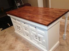 a kitchen island made out of white cabinets and wooden counter tops with drawers on each side