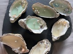 six oysters are arranged on a slate platter, with pearls and seaweed