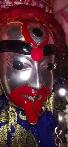 a close up of a person wearing a mask with red eyes and nose rings on their head