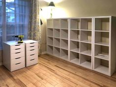 an empty room with white bookcases and wooden floors in front of a window