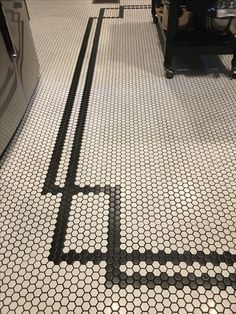 a kitchen floor with black and white tiles on the bottom, an oven in the background