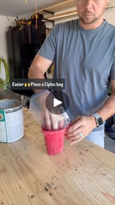 a man pouring something into a cup on top of a wooden table