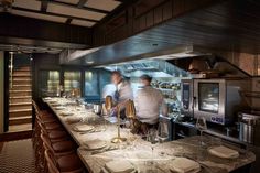 two chefs preparing food in a kitchen with white plates and silverware on the counter