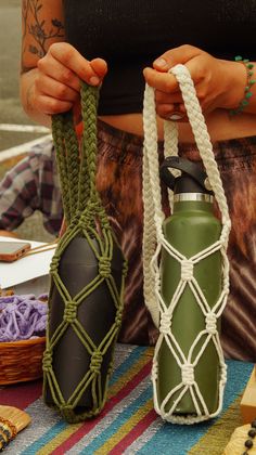 a woman holding two green and white water bottles on top of a colorful table cloth