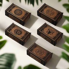 four wooden boxes sitting next to each other on top of a white table with green leaves