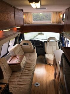 the interior of a vehicle with wood flooring and couches in front of it