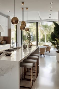 a large kitchen with marble counter tops and white cabinets, along with modern lighting fixtures