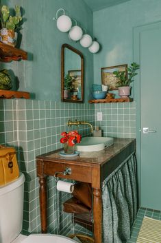 a bathroom with green walls and tile flooring has a sink, toilet, and mirror on the wall