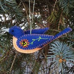 a blue bird ornament hanging from a pine tree