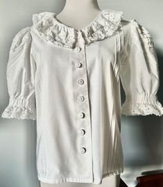 Gorgeous Romantic White DIRNDL TRACHTEN BLOUSE with 2" CROCHET LACE around neckline and sleeves, the Puff Sleeves are beautifully designed with Pleats in 2 different directions, also vertical pleats in the front. the buttons are oldfashioned Linen Buttons, 1 reserve button. Material 50/50 Cotton/Poly Size 38 = US Size 8 actual measurements are: Bust and Waist 38" Length 22" VINTAGE, in excellent condition Crochet Neckline, Sleeve Ruffles, Blouse White, 50 50, Crochet Lace, Puff Sleeves, Shoulder Pads, Womens Clothing Tops, White Cotton