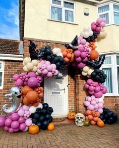 an arch made out of balloons in front of a house with pumpkins and bats on it