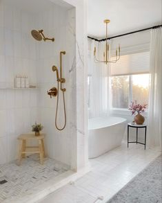 a white bathroom with gold fixtures and marble flooring is featured in this instagram