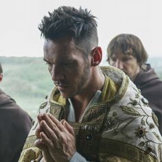 a man with his hands folded in prayer while other men look on from behind him