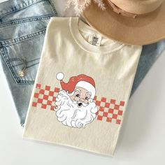 Get into the holiday spirit with our Christmas Comfort Colors Tees! These festive tees offer a blend of vintage style and cozy comfort, making them perfect for all your seasonal celebrations. Whether you're decorating the tree, attending holiday parties, or relaxing with family, these tees bring warmth and cheer to every occasion. 🎄 Key Features: 🧵 100% Ring-Spun Cotton: Experience the softness and durability of premium, ring-spun cotton that feels great all day long. 👕 Vintage-Inspired Look: Each tee features a unique dye process, giving it a classic, faded look that's full of holiday charm. 🌱 Eco-Friendly & Ethically Produced: Feel confident in your purchase with our commitment to sustainable and ethical practices. 🧍 Unisex Sizing: Designed to fit comfortably, our tees are available Retro Christmas Shirts, Vintage Christmas Shirt, Retro Christmas Shirt, Winter Schnee, Retro Santa, Seasonal Celebration, Holiday Colors, Winter Gift, Comfort Colors Tee