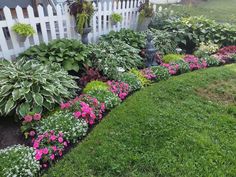 a white picket fence with pink and green flowers in the garden next to some grass