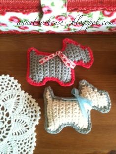 three crocheted dogs sitting on top of a table next to doily and napkins