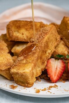 a white plate topped with french toast and sliced strawberries on top of each other