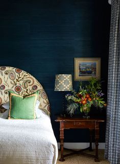 a bedroom with blue walls and white bedding has a green pillow on the headboard