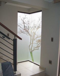 an open door leading to a living room with a tree on the wall and stairs