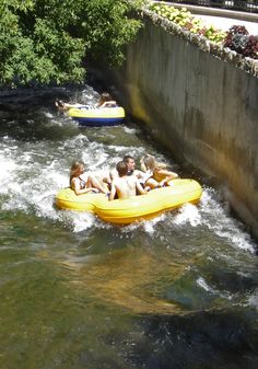 three people are tubling down a small river