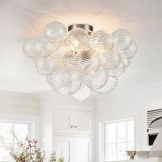 a kitchen with white cabinets and a large glass bowl chandelier hanging from the ceiling