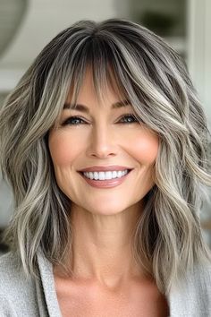 Save this pin for the best medium-length layered haircuts for women over 50. This shaggy cut celebrates your natural hair color. It’s especially flattering for women with salt-and-pepper hair, as the layers allow the blend of greys and silvers to shimmer, almost like highlights. Medium Length Gray Hair With Layers Over 50, Color For Gray Hair Highlights, Natural Grey Hair With Highlights, Highlights On Grey Hair, Salt And Pepper Hair Women, Grey Blending Hair, Shaggy Cut, Shaggy Layers, Medium Length Hair With Bangs