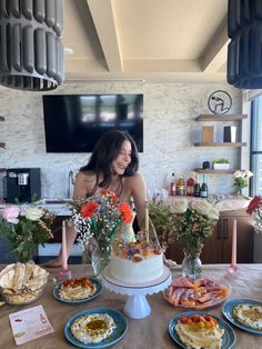 a woman standing in front of a cake on top of a table next to plates of food