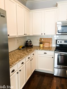 a kitchen with white cabinets and granite counter tops