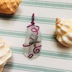 Silver Coated Starfish Charm Wrapped Around A Piece Of Sea Glass Using Magenta Colored Artisan Wire. #Style #Gemstone #Rock #Crystal #Trendy #Handmade #Gift #Her #Gems #Nature #Natural #Stone #Precious #Semiprecious #Statement #Metal #Chakra #Artisan #Chain #Indie #Forest #Intuition #Pride #Color #Luck #Love #Goth #Dainty #Witch #Magic #Beach #Glass #Sea #Fairy #Spring #Summer #Minimalist #Large #Boho #Winter #Fall Silver Wire Wrapped Ocean-themed Jewelry, Silver Wire Wrapped Ocean-inspired Jewelry, Silver Ocean-inspired Wire Wrapped Jewelry, Sea Fairy, Seaglass Jewelry, Ocean Collection, Boho Winter, Starfish Pendant, Witch Magic