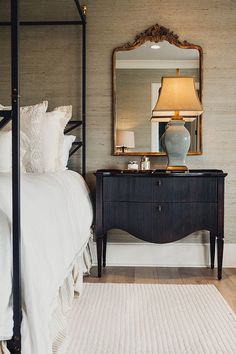 a bedroom with a bed, mirror and lamp on the side table in front of it