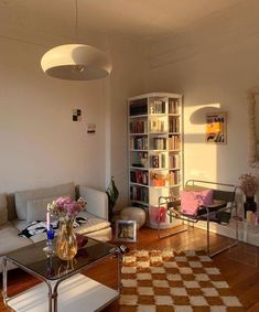 a living room filled with furniture and a book shelf full of books on top of a hard wood floor