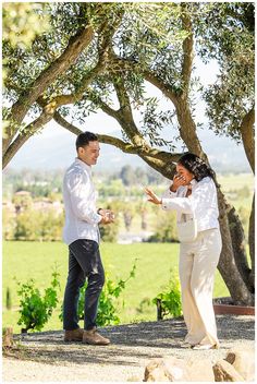 a man and woman standing under a tree