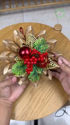 someone is holding a christmas decoration on top of a table