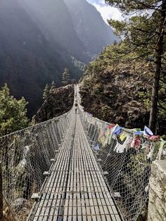 a suspension bridge in the mountains with clothes hanging out to dry on it's sides