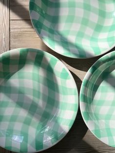 three green and white checkered plates sitting on top of a wooden table next to each other