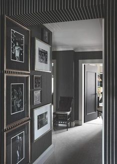 a black and white striped wall with pictures on it's sides, along with a chair in the middle