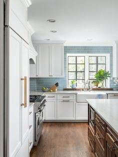 a large kitchen with white cabinets and wood flooring, along with an island in the middle