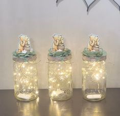 three jars with lights in them sitting on a table