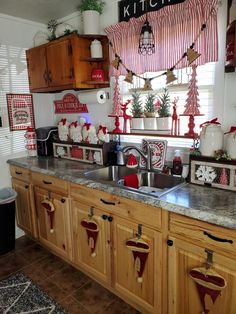 the kitchen is decorated for christmas with red and white decorations on the counter top, and wooden cabinets