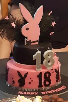 a pink and black birthday cake with rabbit ears on top