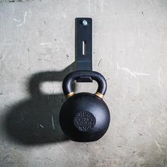 a black kettle sitting on top of a cement floor next to a metal barbell