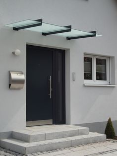 the front door of a white house with black doors and steps leading up to it