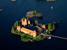 an island with a castle on it in the middle of water surrounded by land and trees