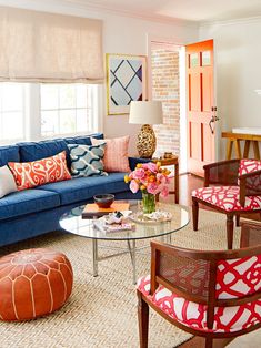 a living room with blue couches and colorful pillows on the chairs, coffee table