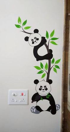 the pandas are hanging from the tree on the wall