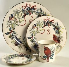 a set of christmas themed dinnerware with holly and cardinals