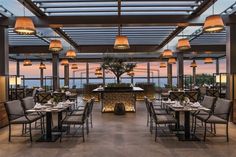 an outdoor dining area with tables, chairs and lamps on the ceiling is lit up at night