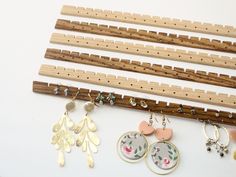 several pairs of earrings are hanging from clothes pegs on a white surface next to other items