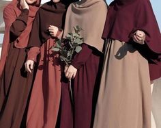 three women dressed in maroon and brown standing next to each other with one holding a flower