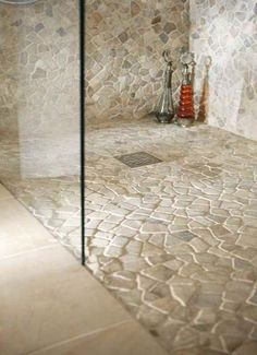 a glass shower door in a bathroom with stone walls and floor tiles on the wall